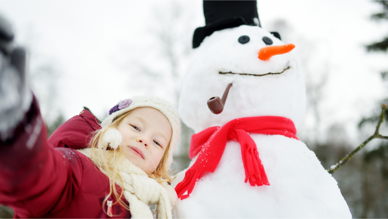 Daughter taking selfie with snowman